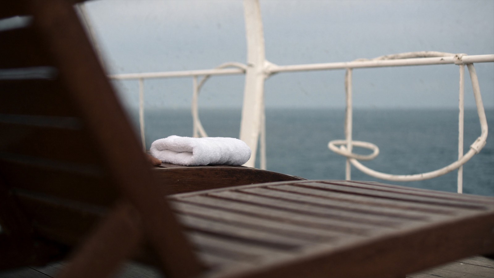A folded white towel on a wooden deck chair